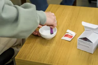En hand som blandar probiotika i en liten vit skål med en spruta. Foto.